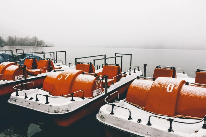 ac864ab9-ffb0-4683-9961-79252fd1ffc1-orange-paddleboats-by-pier-calm-lake-captured-foggy-winter-day.jpg